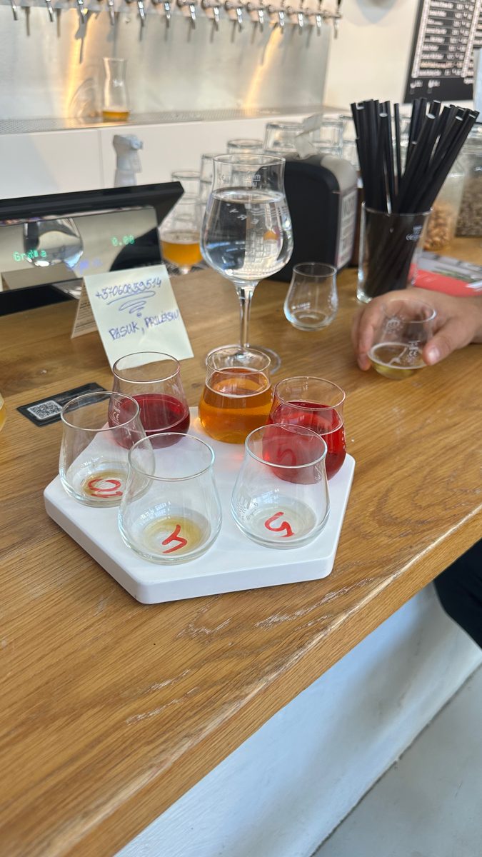 A tasting flight of five small beers on a wooden bar.